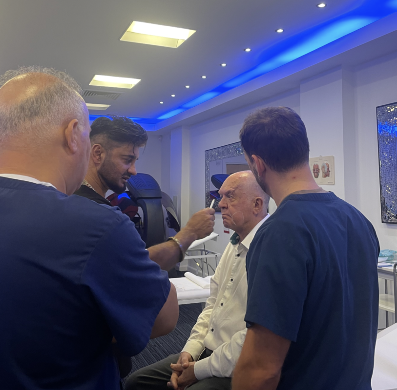 A group of medical professionals in a brightly lit clinic examining a man sat down