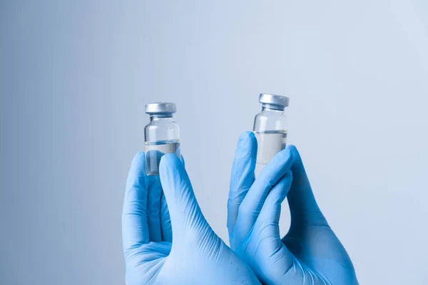 Two vials being held by hand in gloves