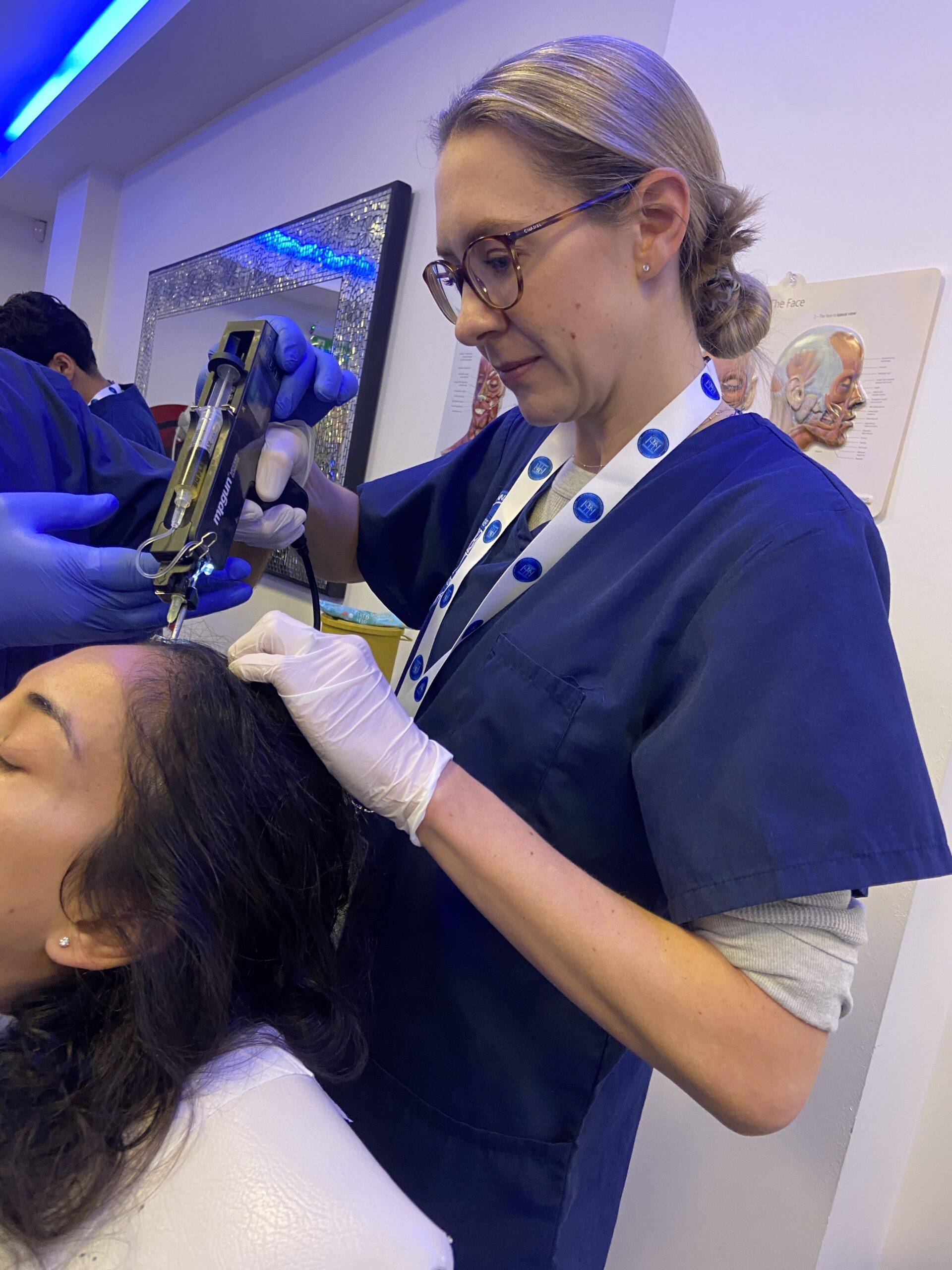 Image of a woman on a training course, injecting polynucleotides into a model's scalp for anti-hair loss