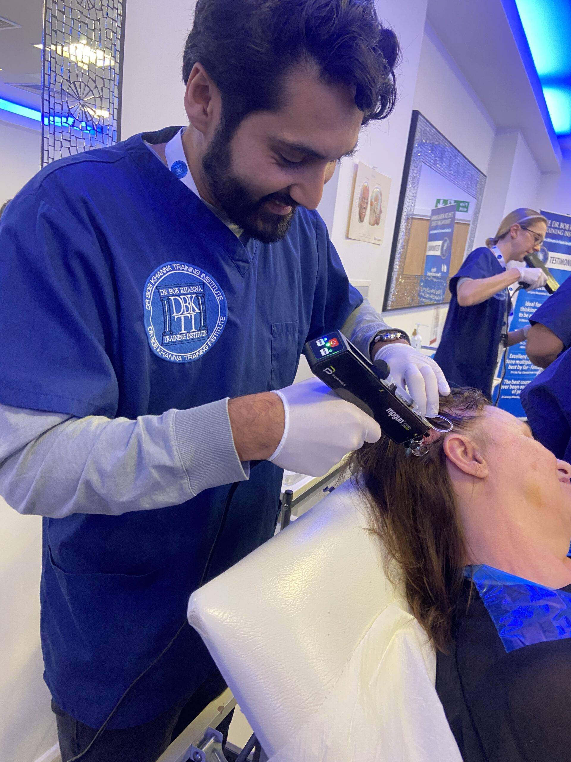 Image of a man on a training course, injecting polynucleotides into a model's scalp for anti-hair loss